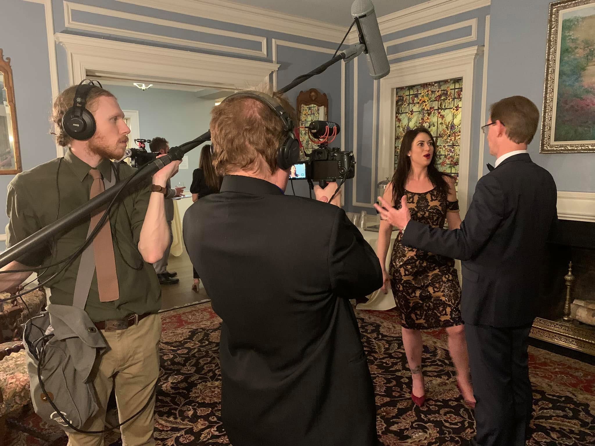 Behind the scenes of a Regret-Free Productions shoot — boom operator, camera operator, and two people being filmed